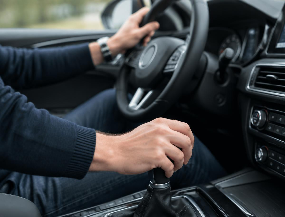 Learner's hands on the gear stick and steering wheel during a driving lesson